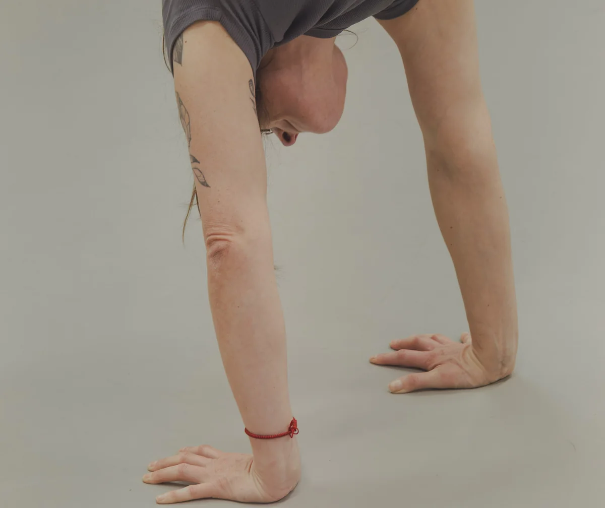 Hands pressing into the floor during a handstand kick-up, head between the arms