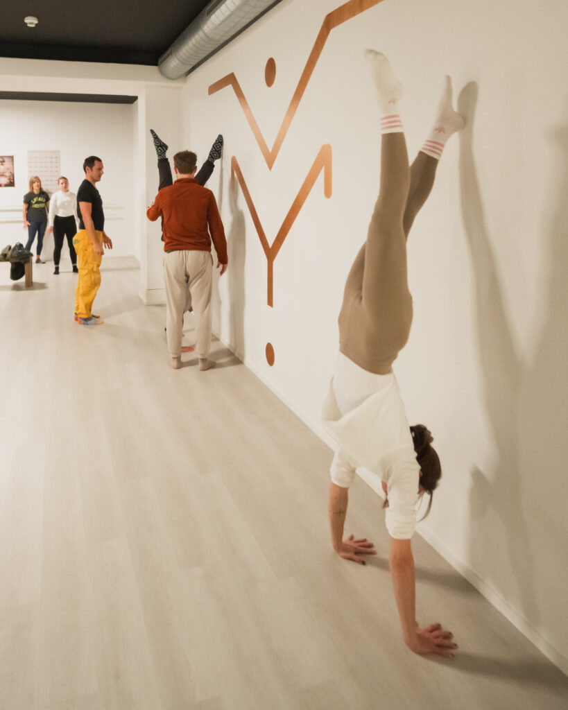 Teilnehmende üben den Handstand an der Wand